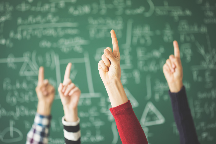 multiple hands in the air in front of a chalkboard
