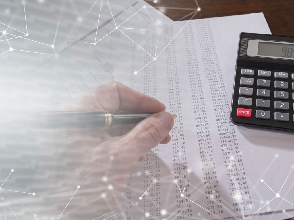 hand writing on paper full of numbers with calculator to the right