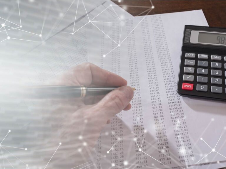 hand writing on paper full of numbers with calculator to the right